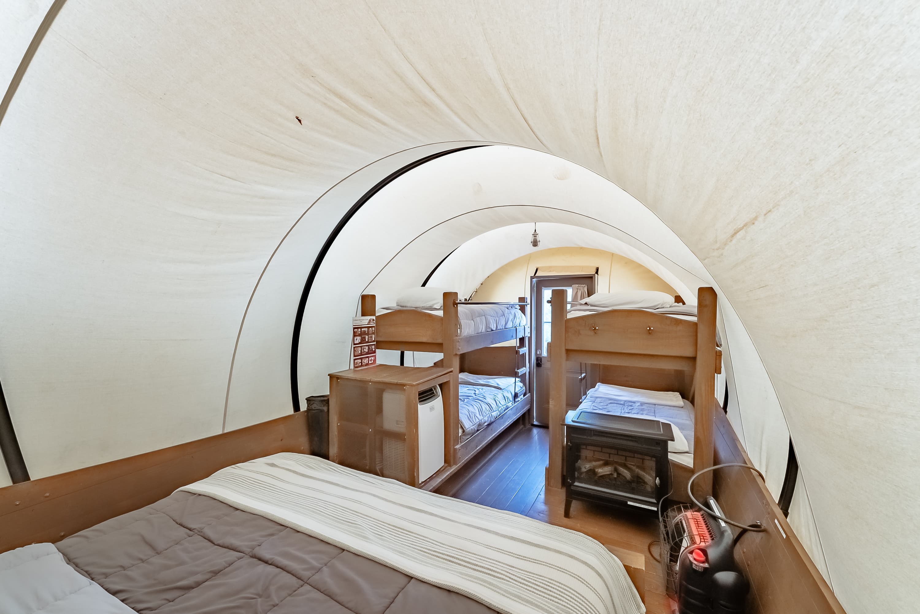 Interior of a cozy tent with stacked bunk beds and a warm atmosphere.