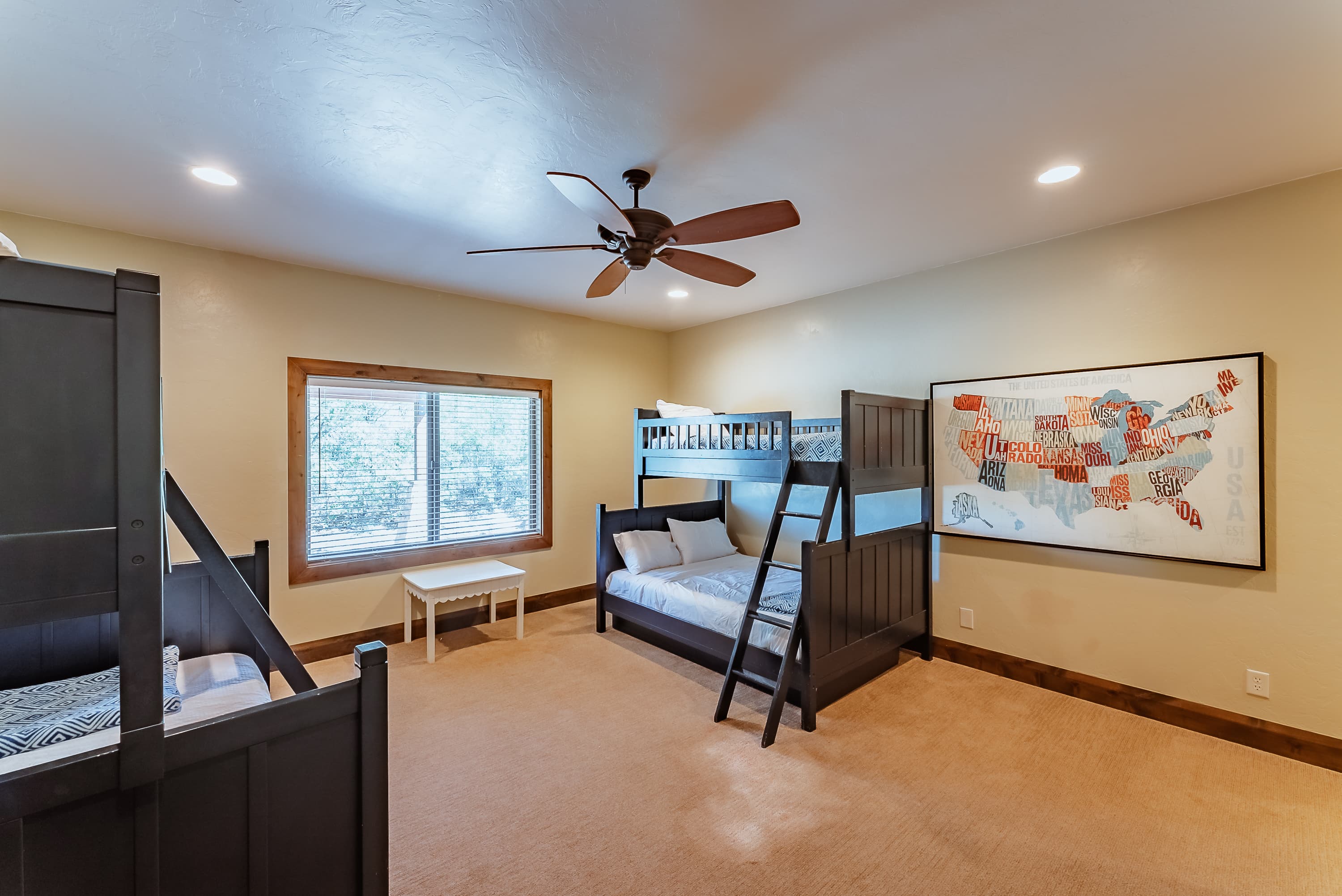 A cozy bedroom featuring two bunk beds, a ceiling fan, and a map print on the wall.