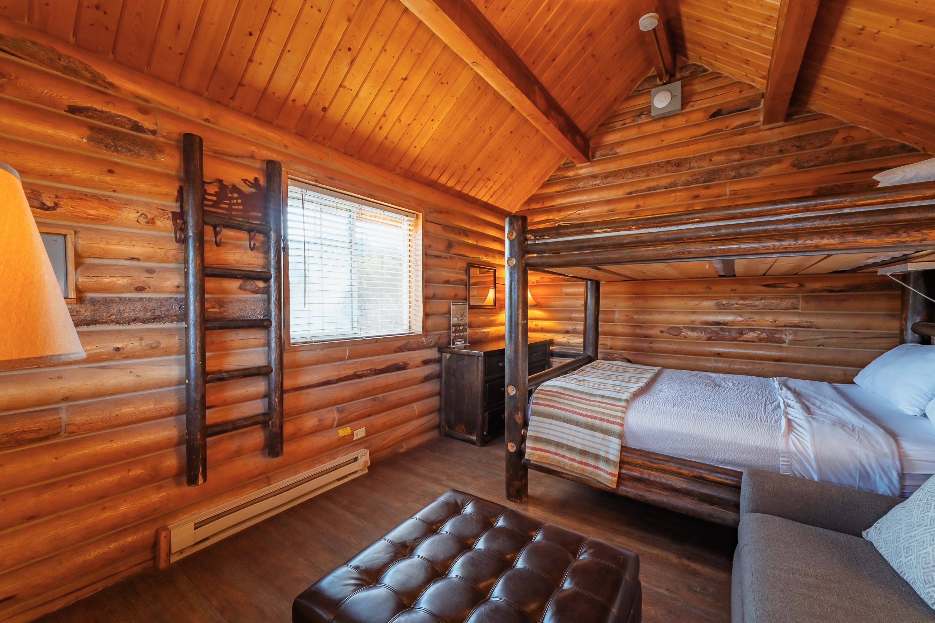 A cozy log cabin interior featuring a bed, seating area, and wooden accents.