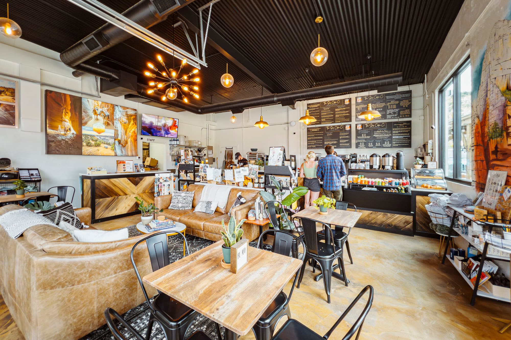 Cozy coffee shop interior featuring seating areas, a coffee counter, and vibrant artwork.