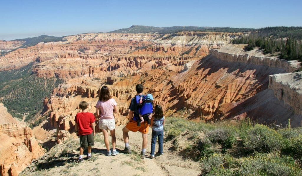 A family of four stands on a canyon overlook, admiring the colorful rock formations beyond.