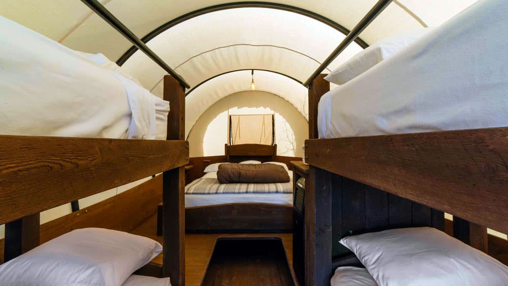Interior view of a cozy tent with two sets of bunk beds and a central double bed.