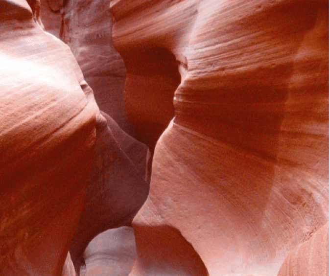 A narrow, winding canyon with smooth, reddish rock formations.