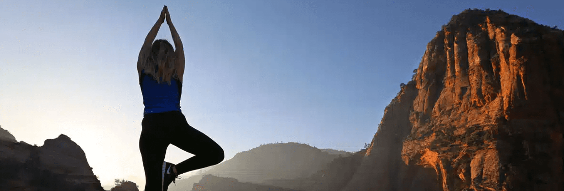 A person practicing yoga in a mountain landscape at sunrise.