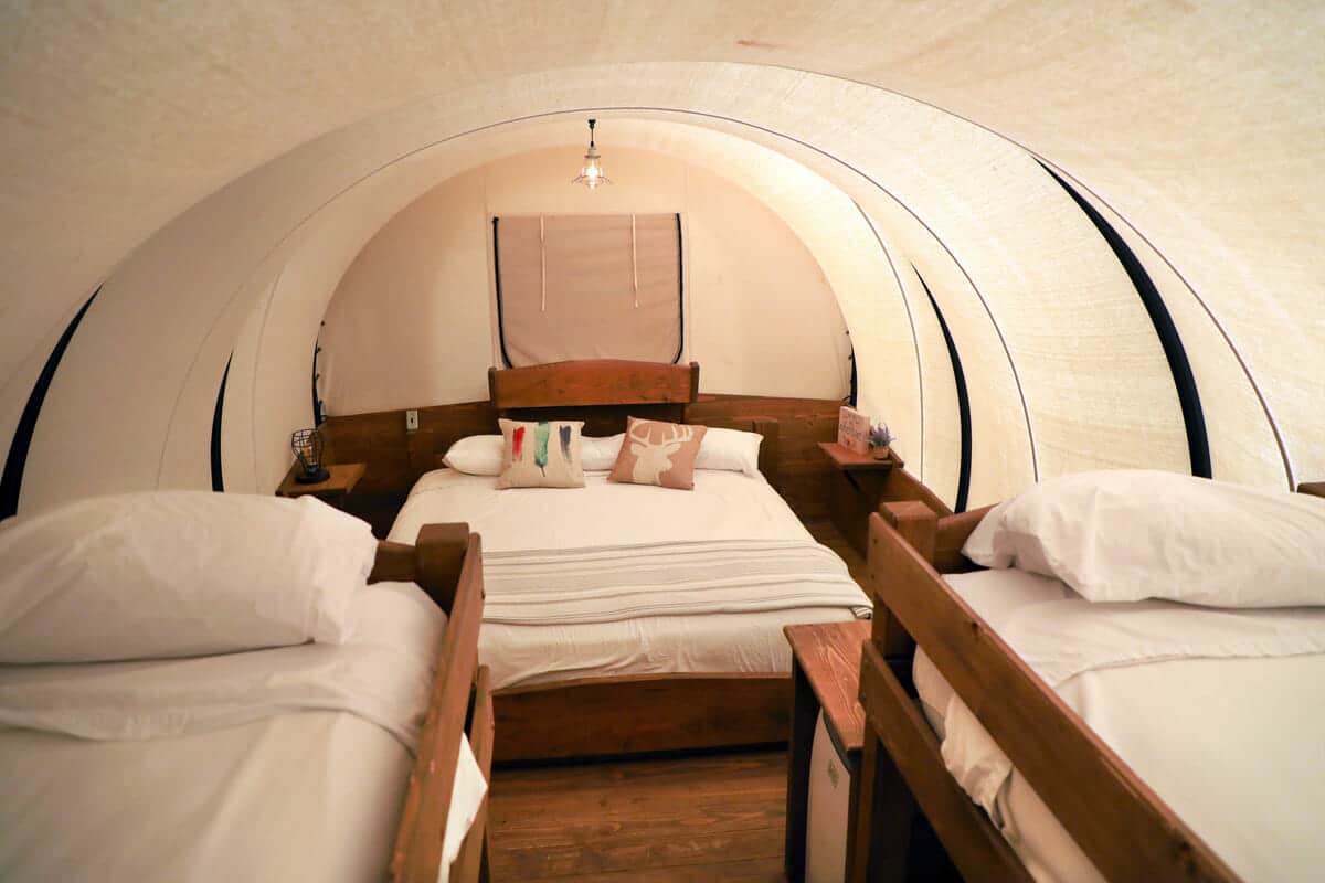 Cozy, tent-like bedroom featuring a large bed and two smaller beds with white linens and decorative pillows.