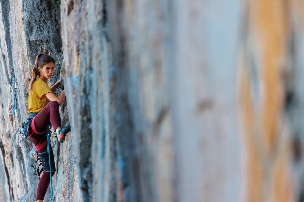 A climber ascends a rocky wall, focused and determined.
