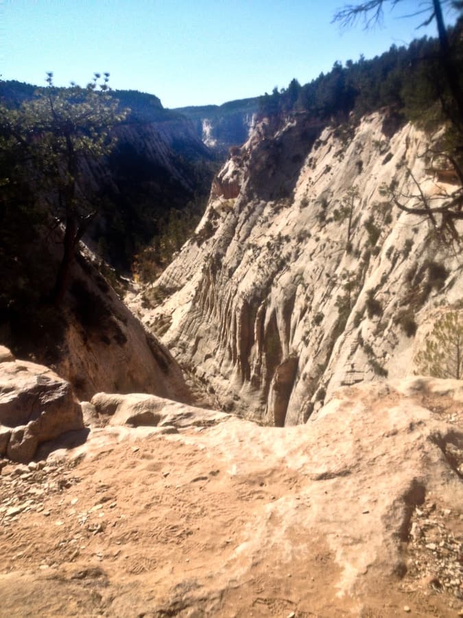 A steep canyon with textured rock formations under a clear blue sky.