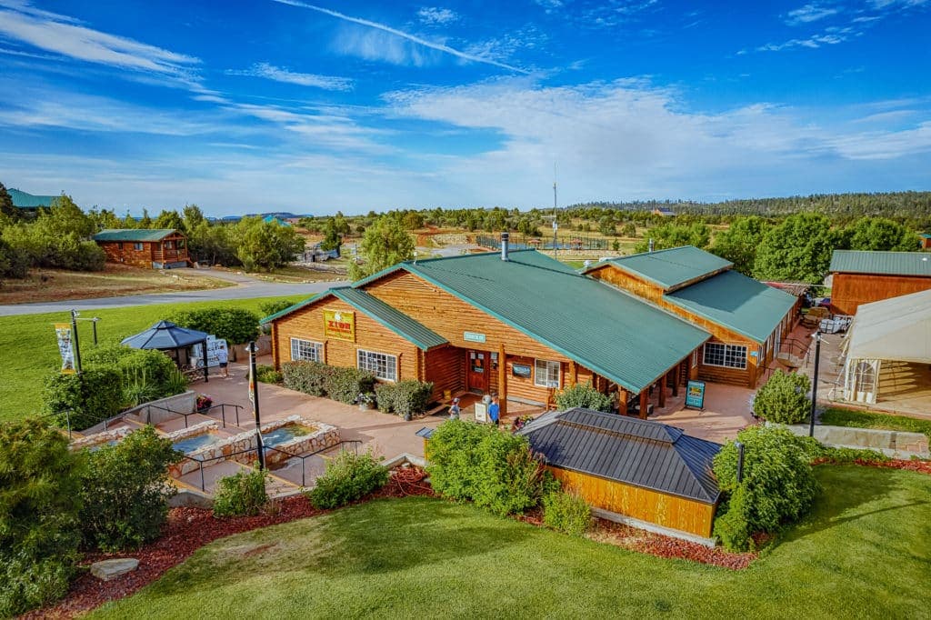 Aerial view of a rustic lodge surrounded by greenery and a clear blue sky.