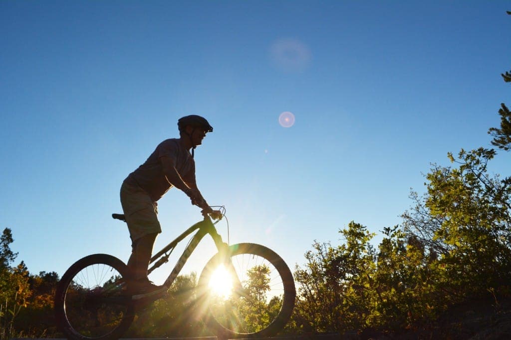 A silhouette of a person riding a bicycle at sunset.