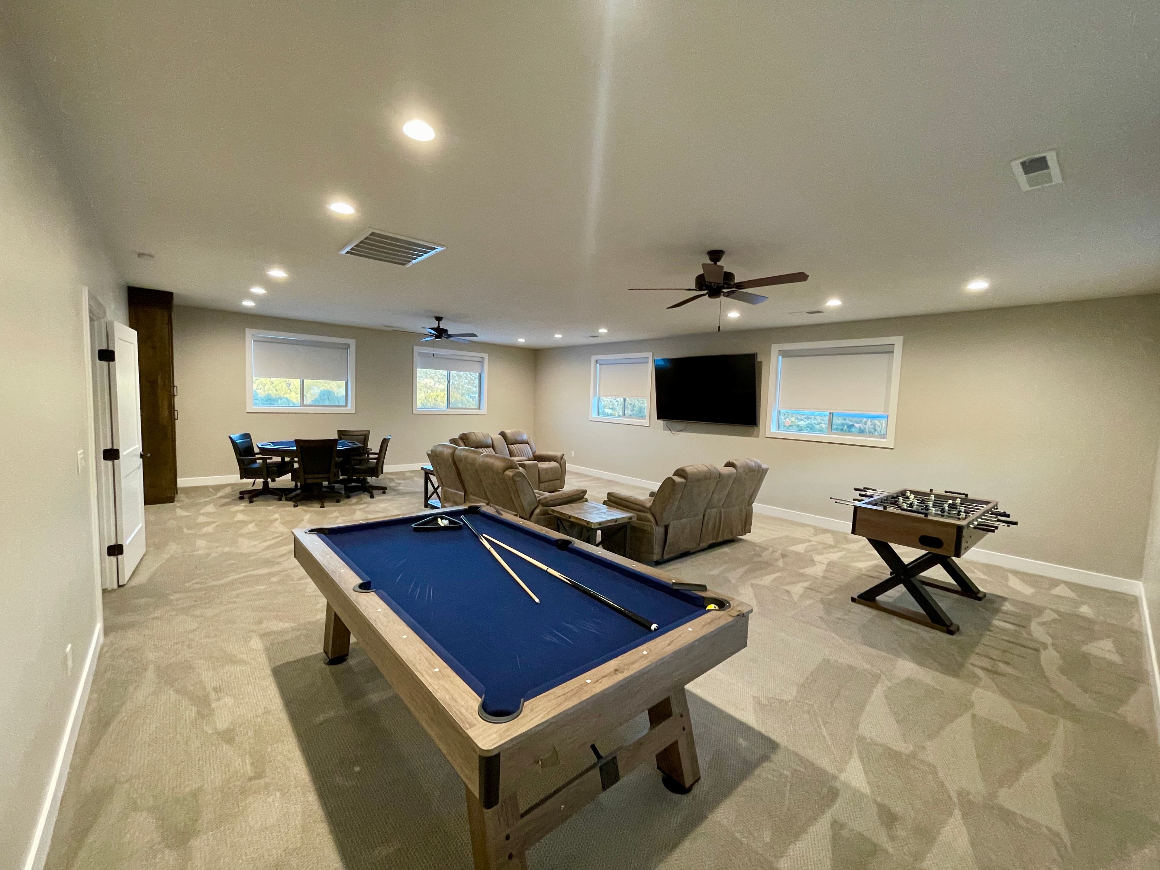 A spacious game room featuring a pool table, comfortable seating, and a dining area.