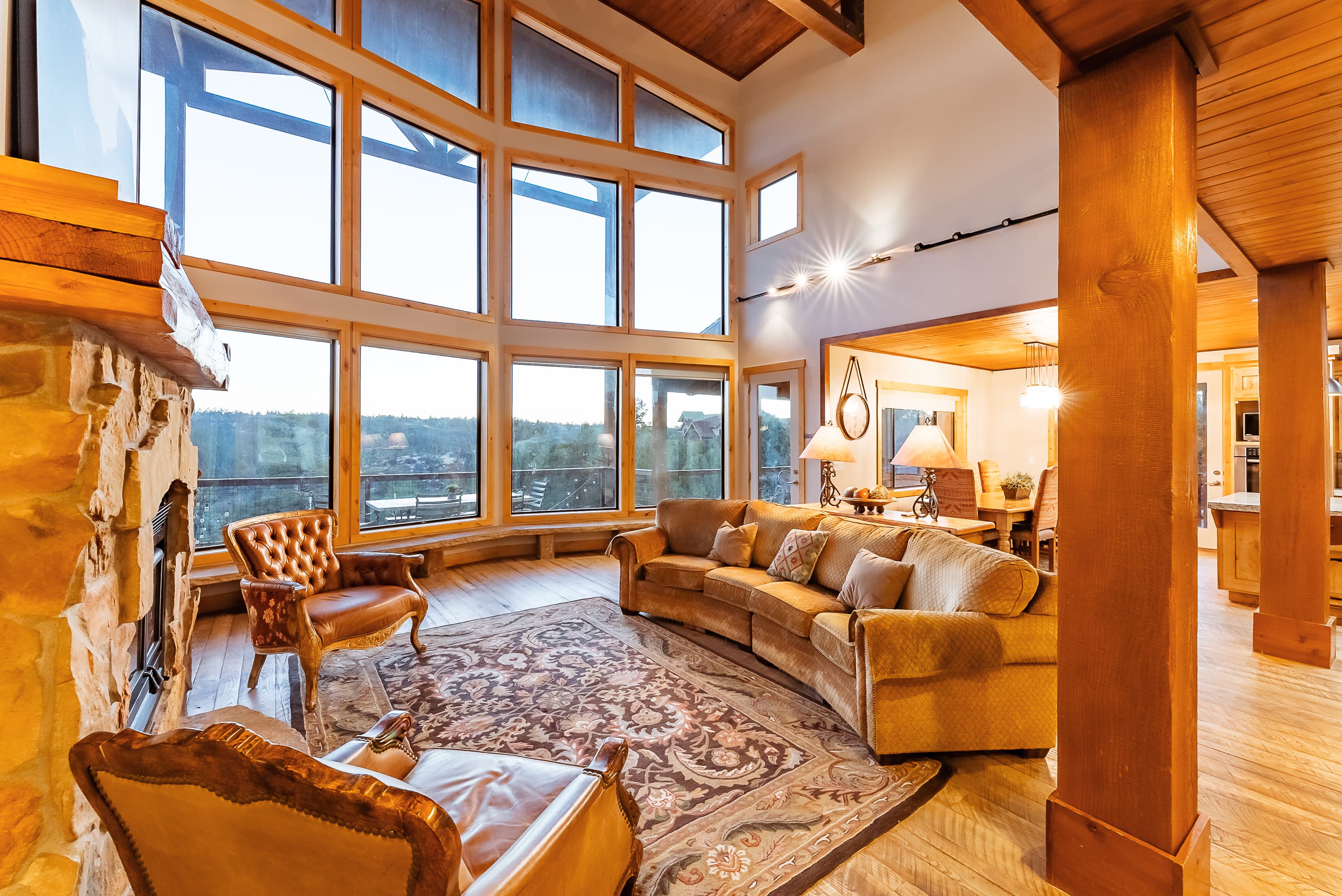 Modern living room featuring large windows, a stone fireplace, and comfortable seating.