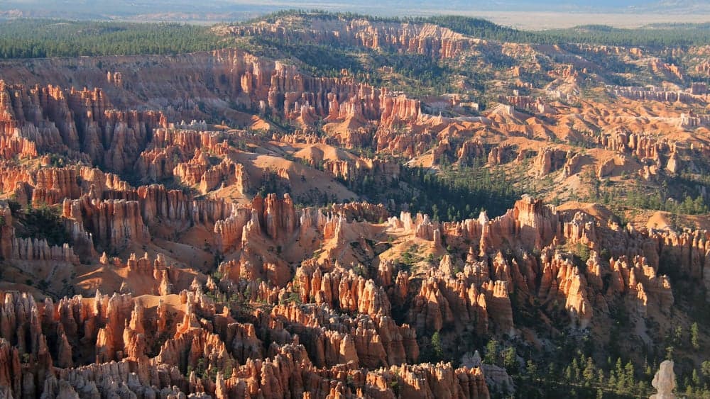 A panoramic view of red rock formations and hoodoos in a canyon landscape.