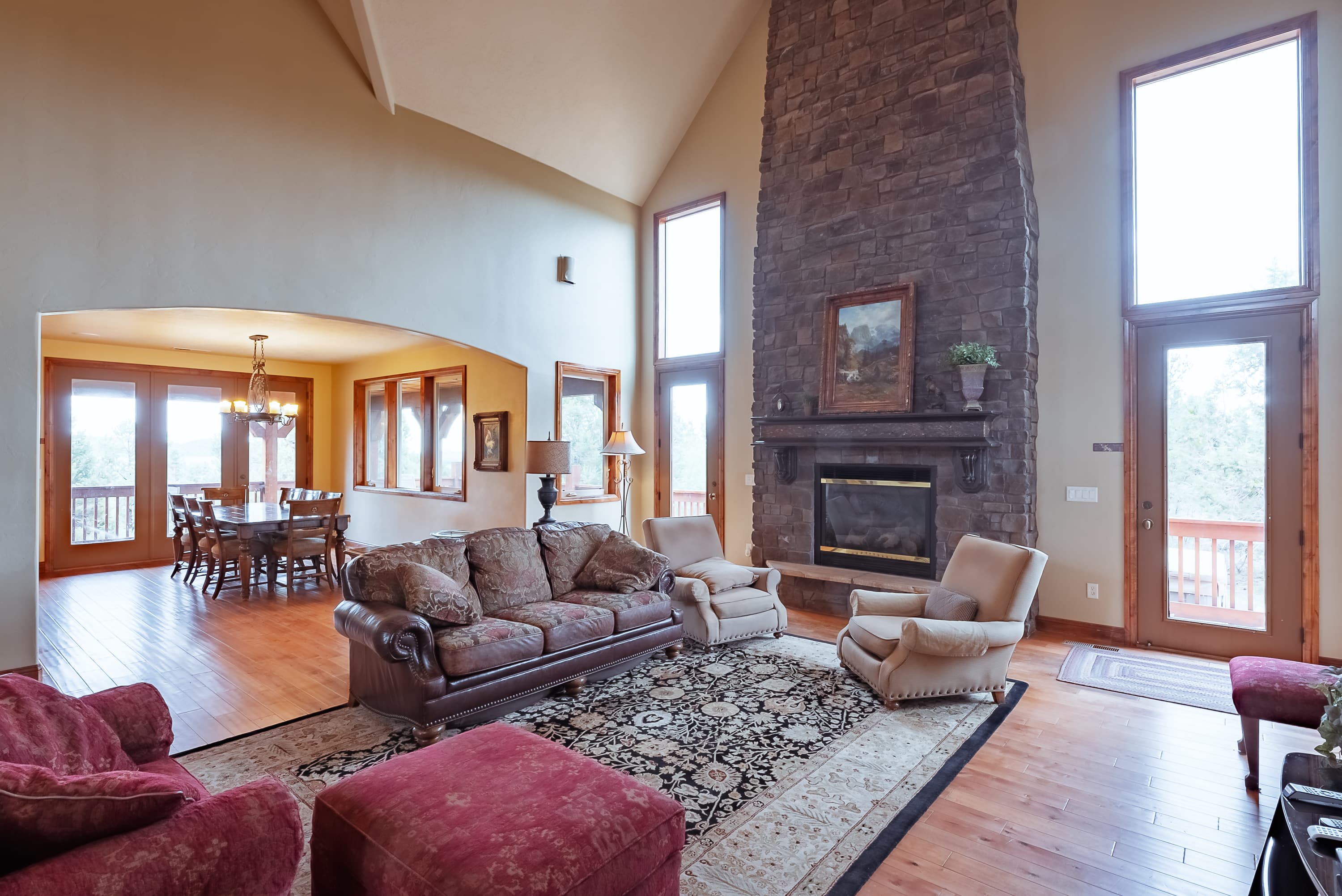 A spacious living room with a stone fireplace, large windows, and comfortable seating.