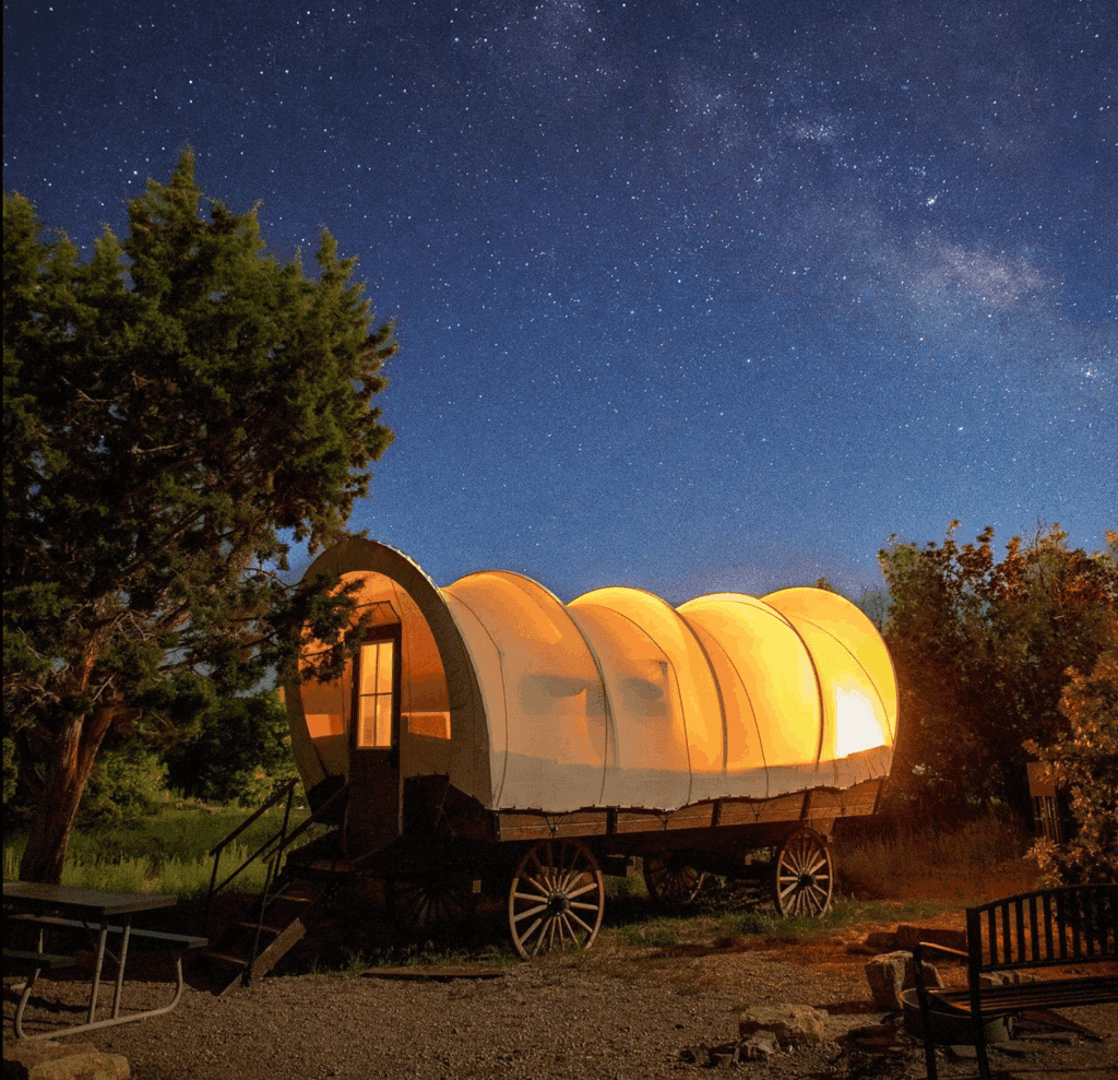 A vintage wagon illuminated against a starry night sky.