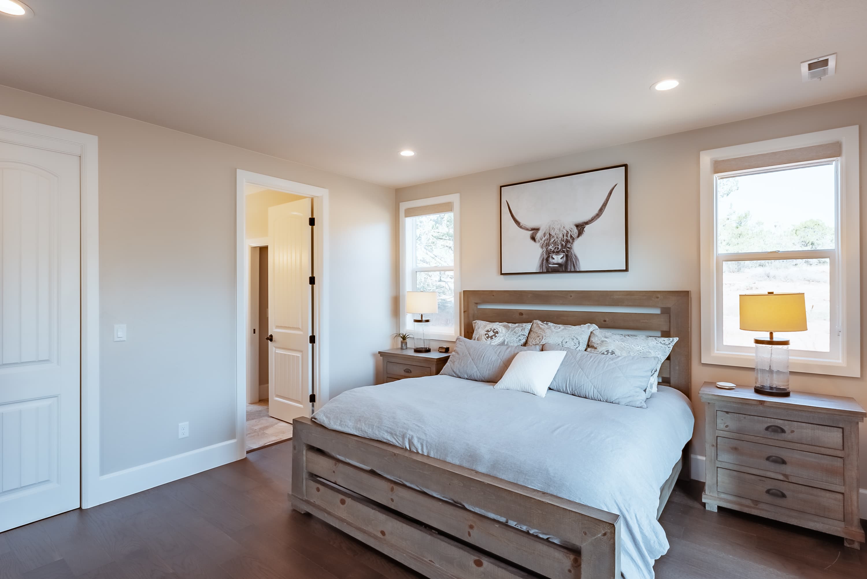 A cozy, well-lit bedroom featuring a wooden bed, bedside tables, and an animal-themed artwork on the wall.