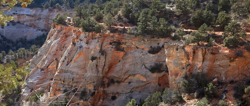 A scenic view of a steep cliffside surrounded by green trees and rocky terrain.