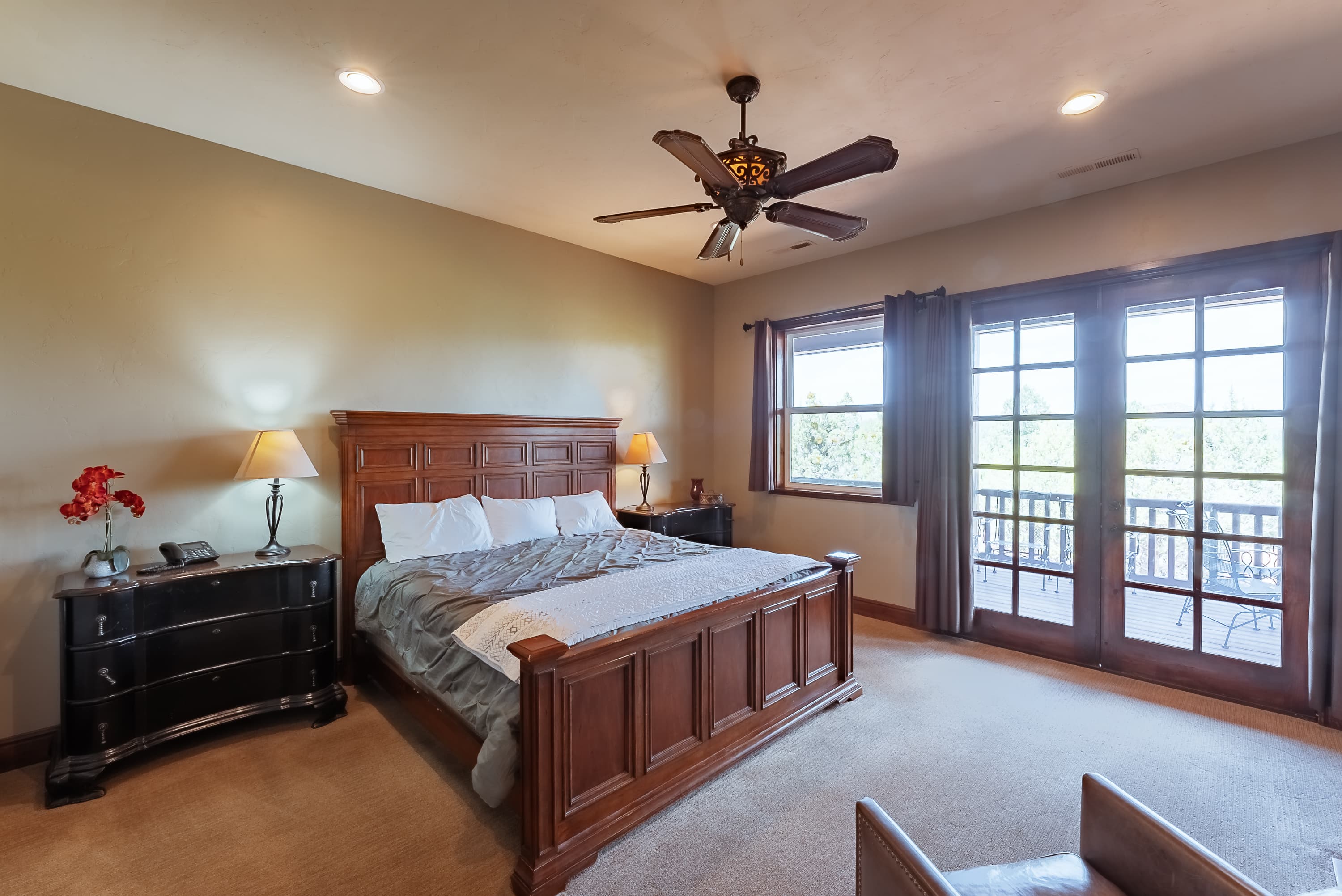 Spacious bedroom with wooden furniture, a ceiling fan, and balcony access.