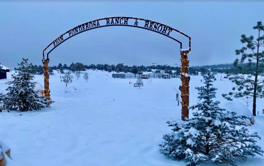 Entrance archway of Zion Ponderosa Ranch & Resort surrounded by a snowy landscape.