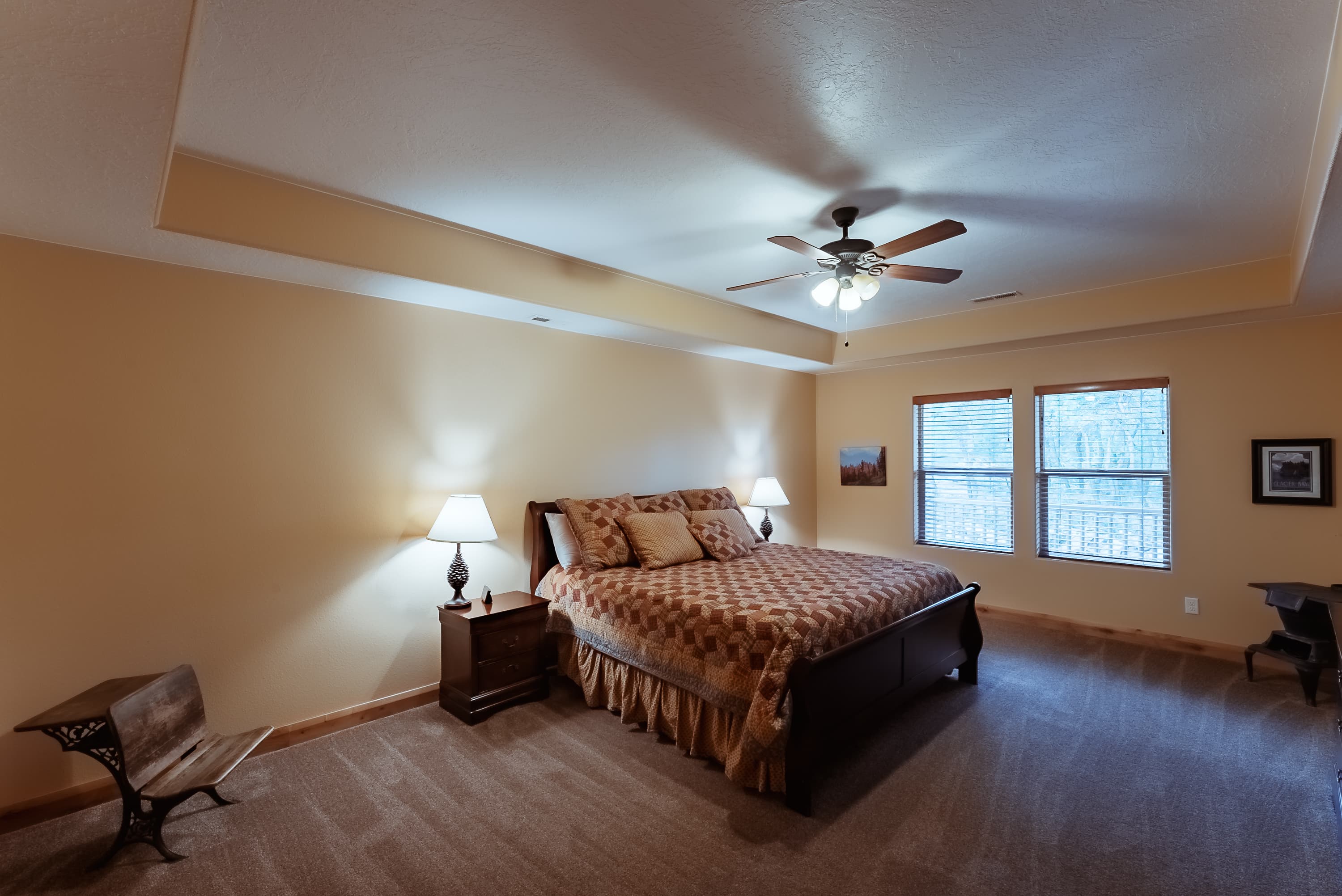 Spacious bedroom with a queen bed, bedside lamps, and large windows.