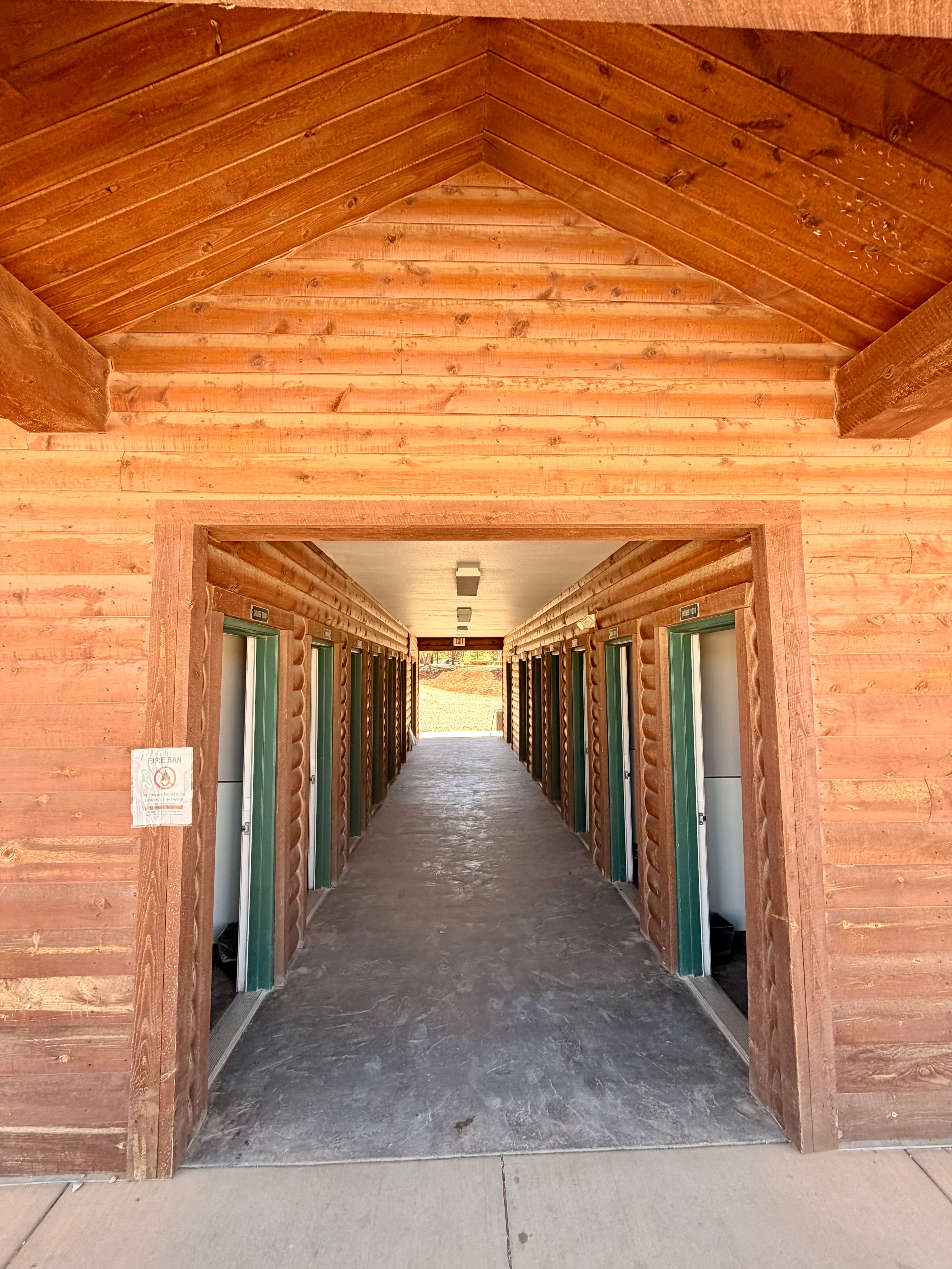 Interior view of a long hallway lined with storage unit doors within a wooden building.