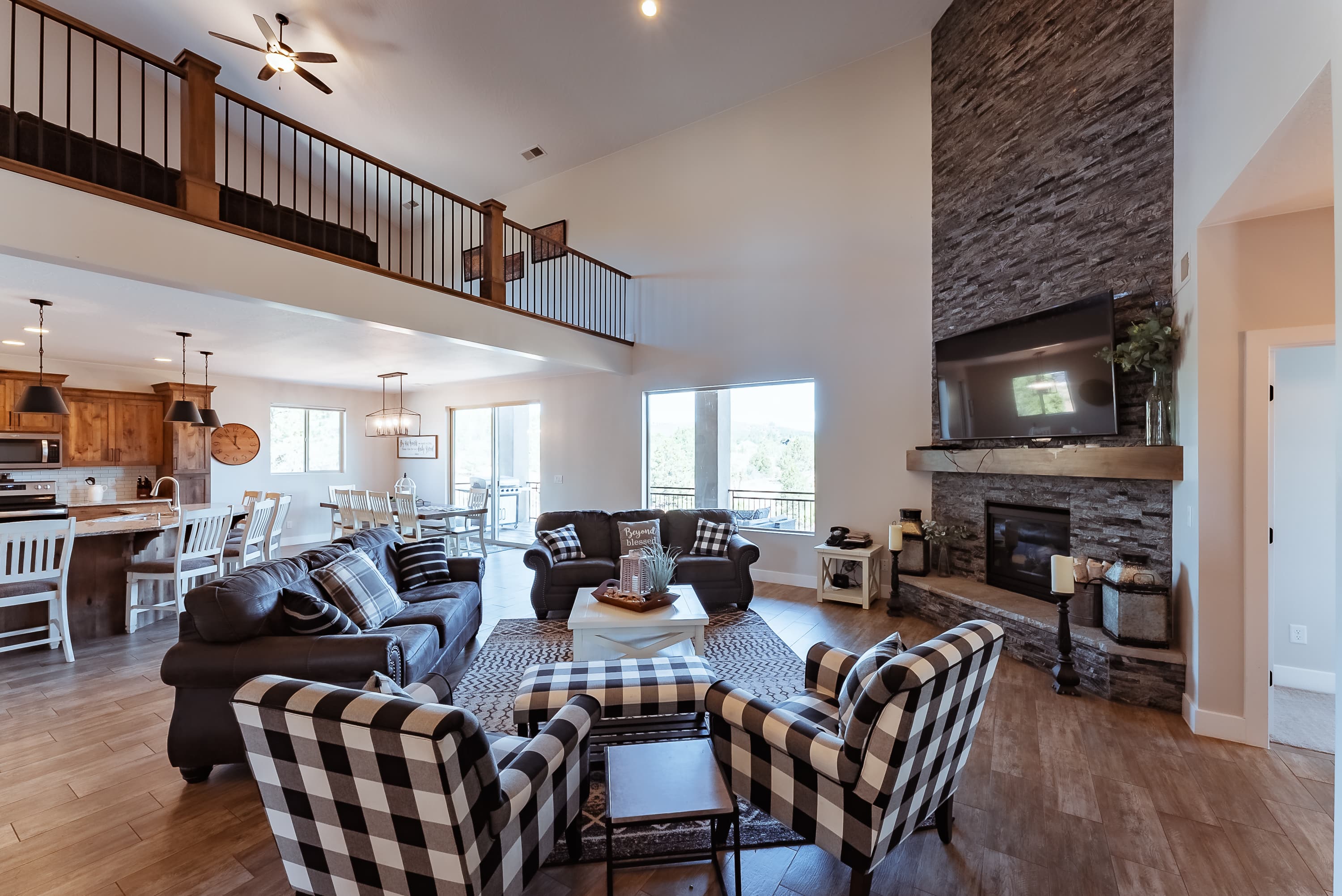 Spacious living room with a stone fireplace, modern furniture, and large windows allowing natural light.