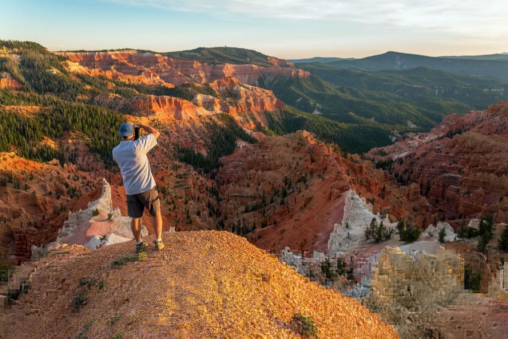 A person stands on a cliff overlooking a colorful canyon landscape.