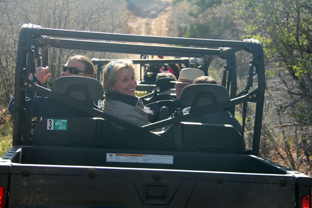 A group of people enjoys a ride in off-road vehicles on a dirt trail.