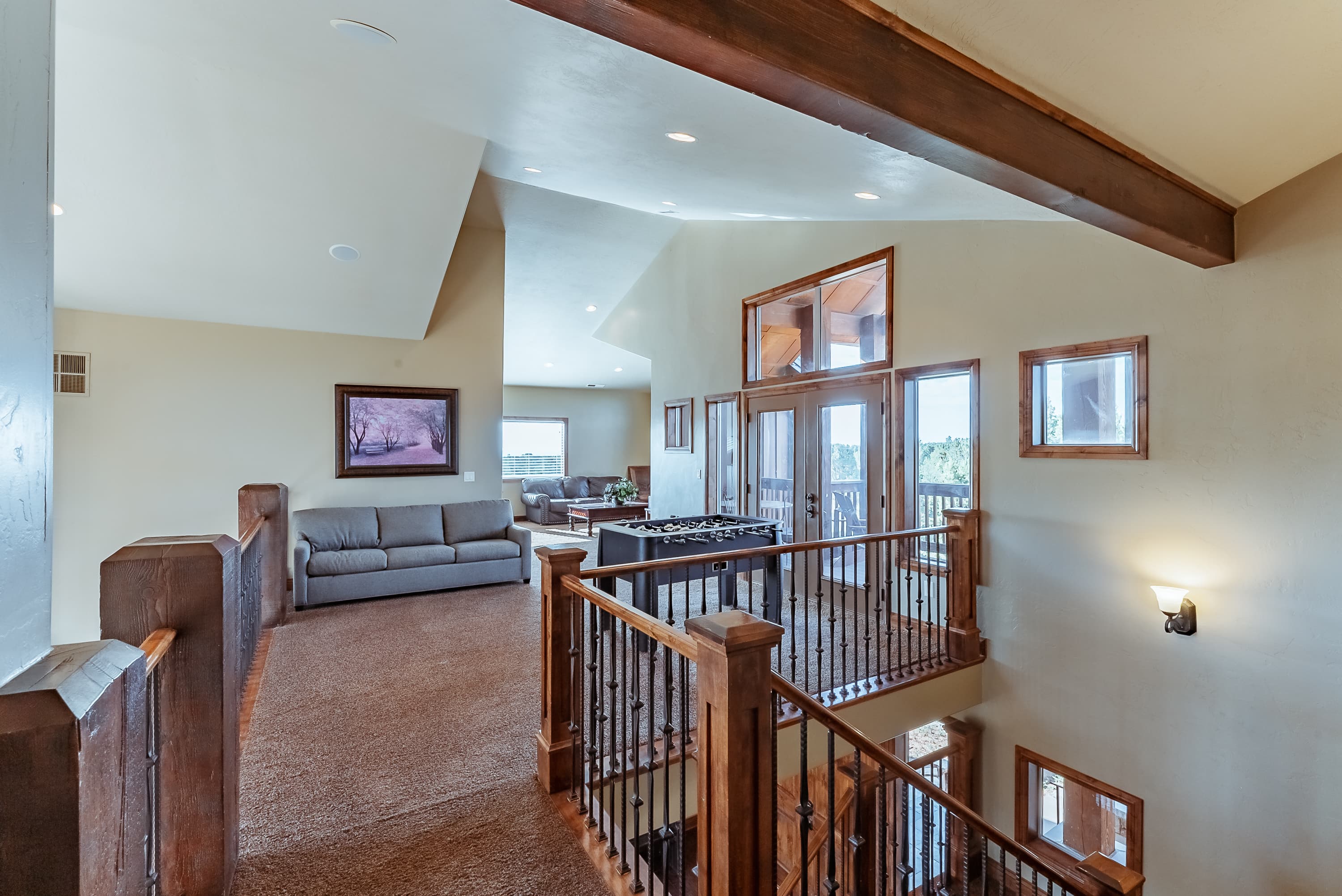 A spacious, well-lit interior view of a modern home featuring a staircase, seating area, and large windows.