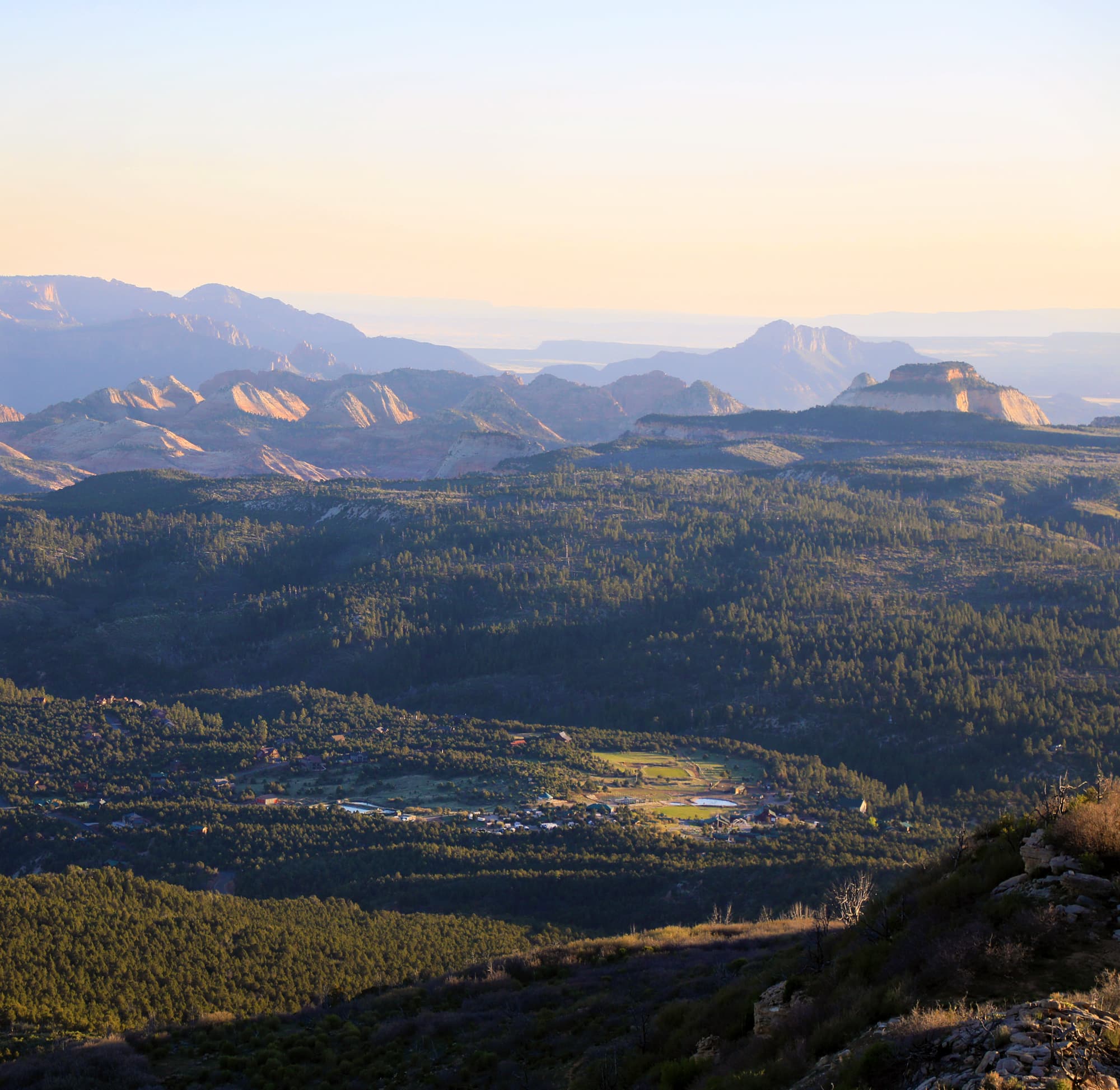 A panoramic view of layered mountains and valleys at sunset.