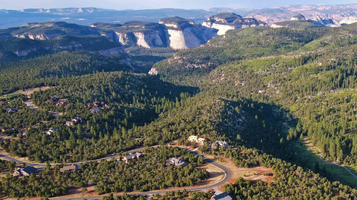 Aerial view of a lush, green valley surrounded by rugged cliffs and winding roads.