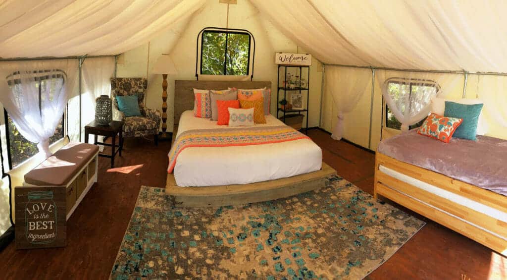 Cozy glamping tent interior featuring a double bed, a twin bed, and decorative furnishings.