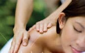 A woman receiving a massage outdoors with a natural background.
