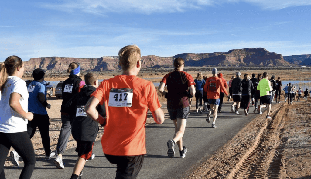 A group of runners participates in a race along a path with a scenic mountainous background.
