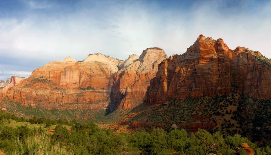 A panoramic view of red rock cliffs under a blue sky in Zion National Park.