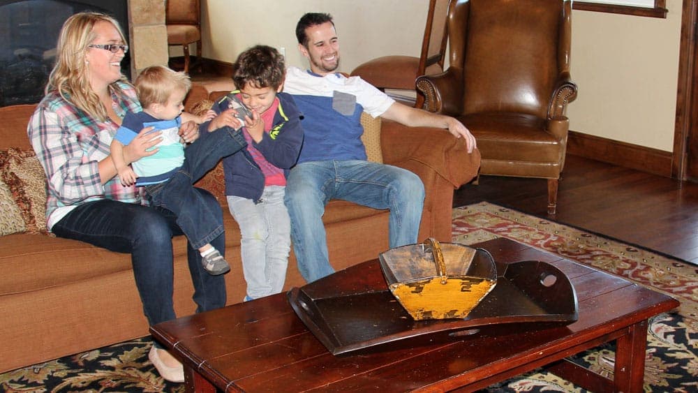 A family sits together on a couch, enjoying time with two young children.