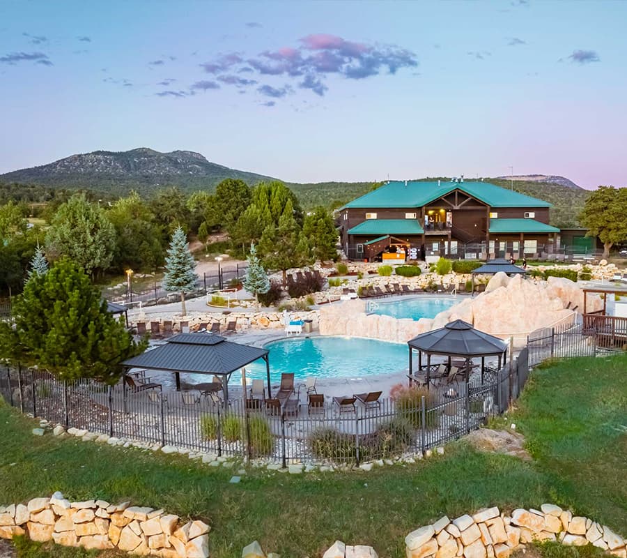 A scenic view of a resort pool area surrounded by mountains and lush greenery.