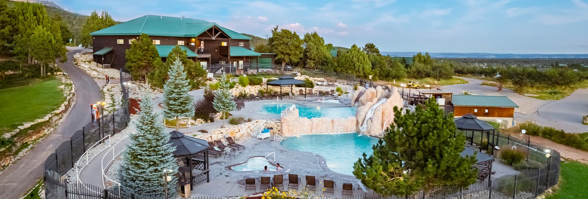 Aerial view of a resort featuring a pool area surrounded by trees and rocky landscape.