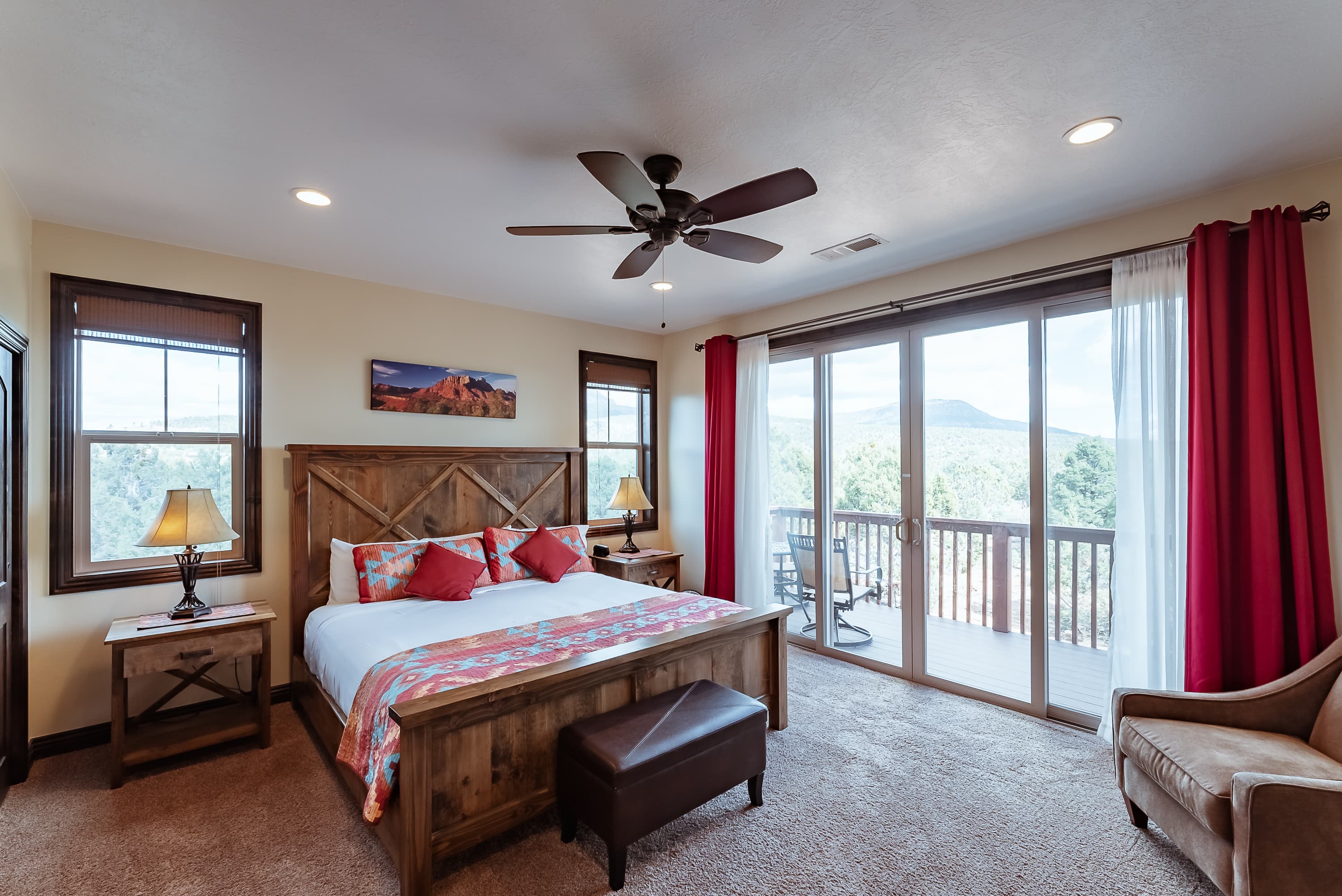 A cozy bedroom featuring a queen-size bed, wooden furniture, sliding glass doors, and mountain views.