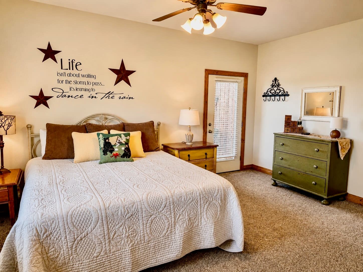 A cozy bedroom with a large bed, green dresser, and inspirational wall decor.