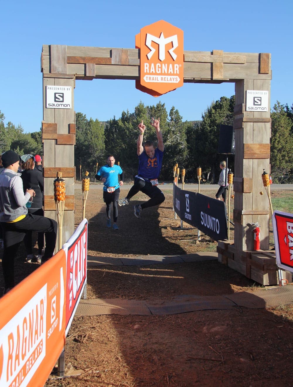 A runner leaps joyfully across the finish line at the Ragnar Trail Relays event.