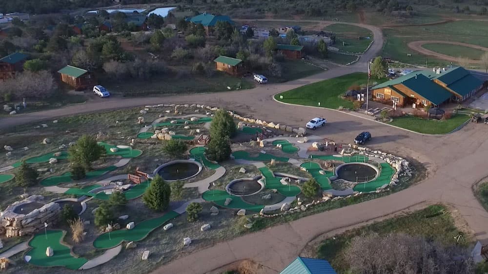 Aerial view of a mini-golf course surrounded by cabins and greenery.