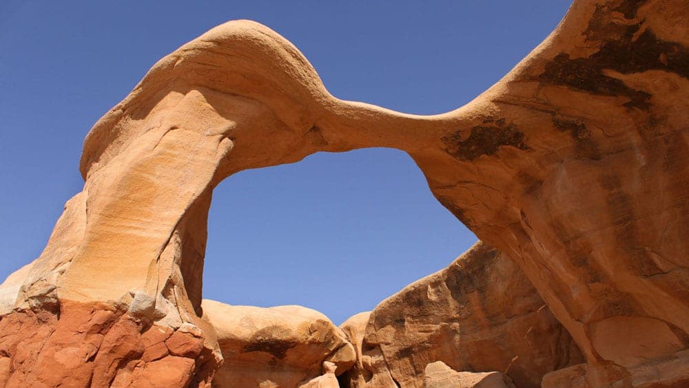 A natural sandstone arch against a clear blue sky.