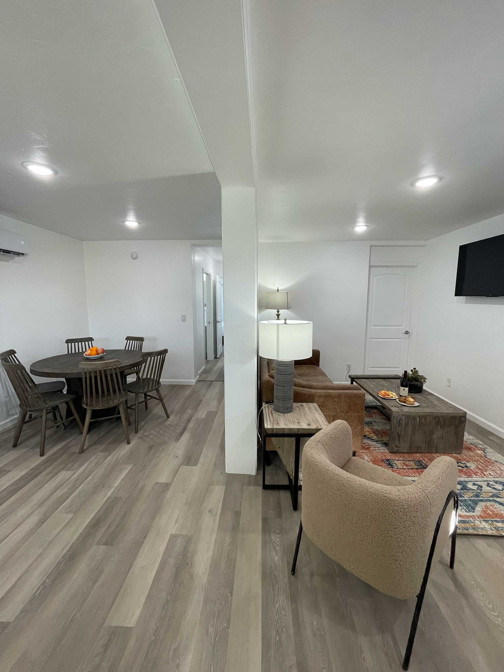 A modern living space featuring a dining area with a round table, a cozy seating area, and warm lighting.