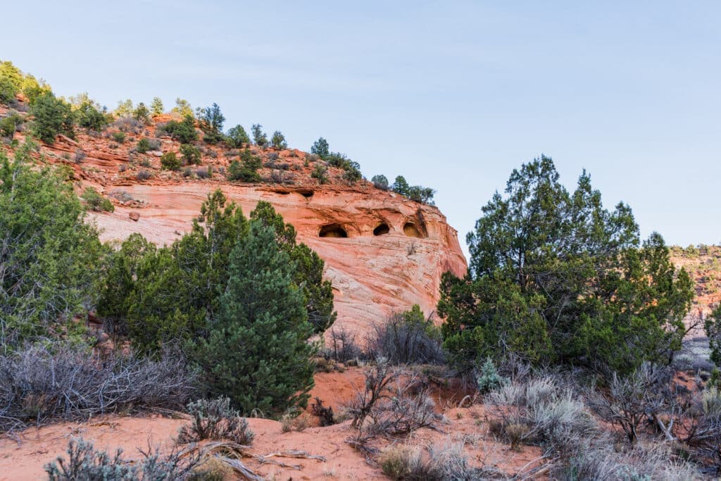 Rocky landscape with foothills and lush greenery under a clear sky.