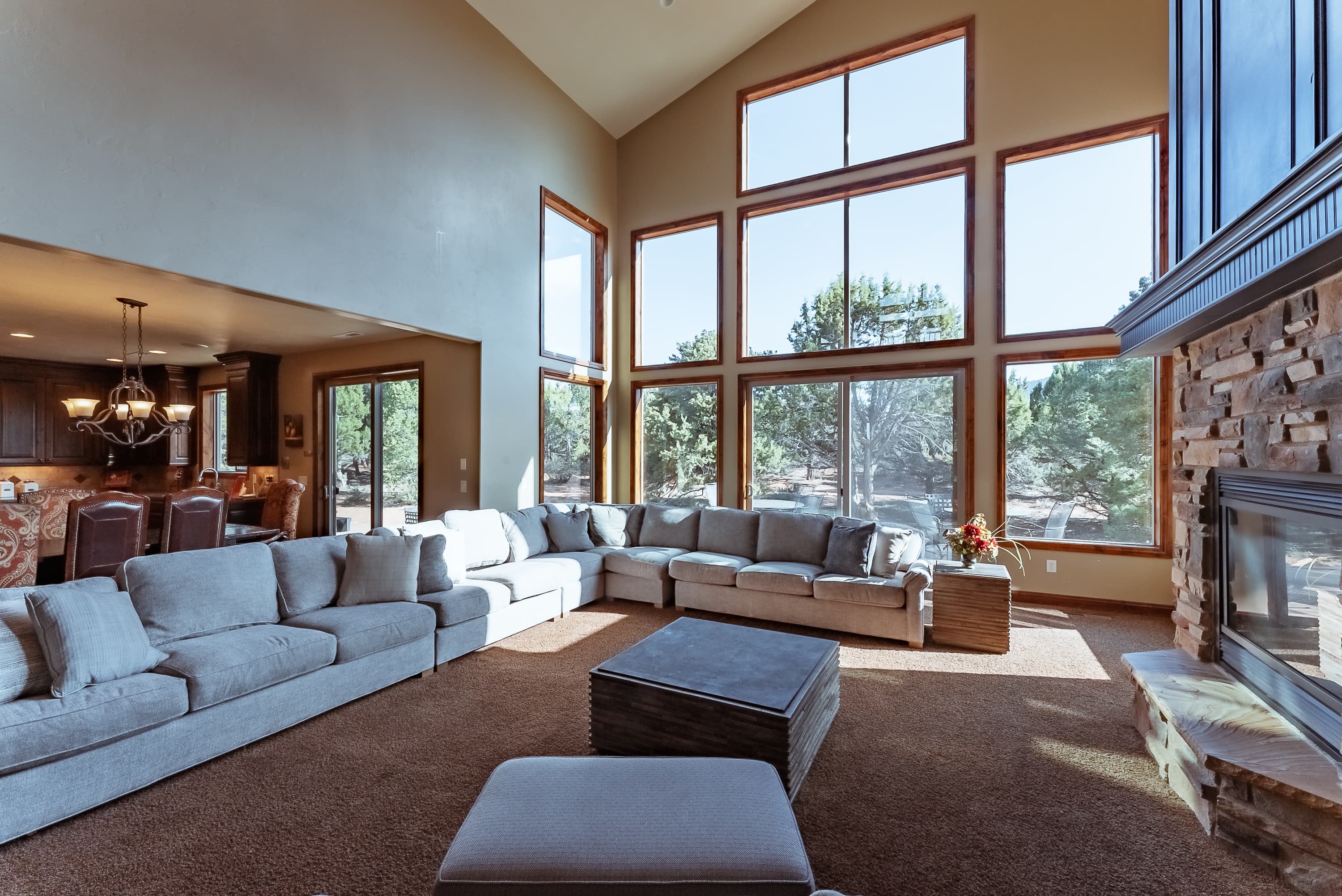 Bright, spacious living room with large windows, a sectional sofa, and a cozy fireplace.