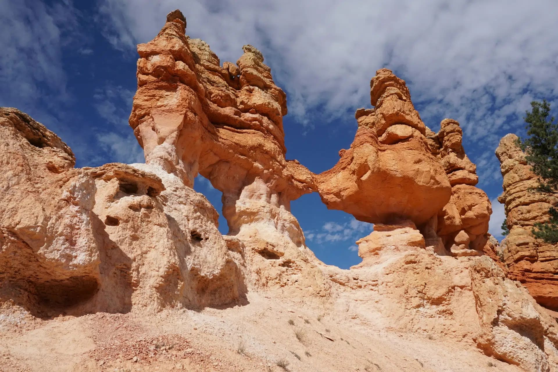 A unique rock formation with reddish hues and a natural arch under a blue sky.