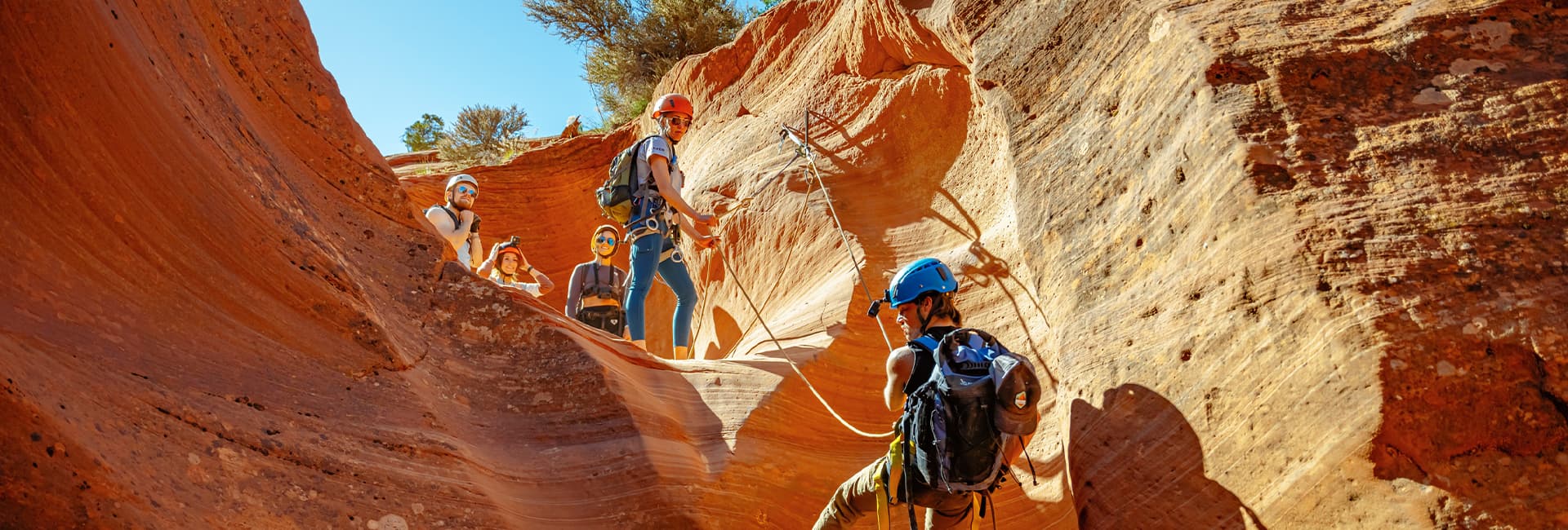 A group of climbers navigates through a colorful canyon landscape.