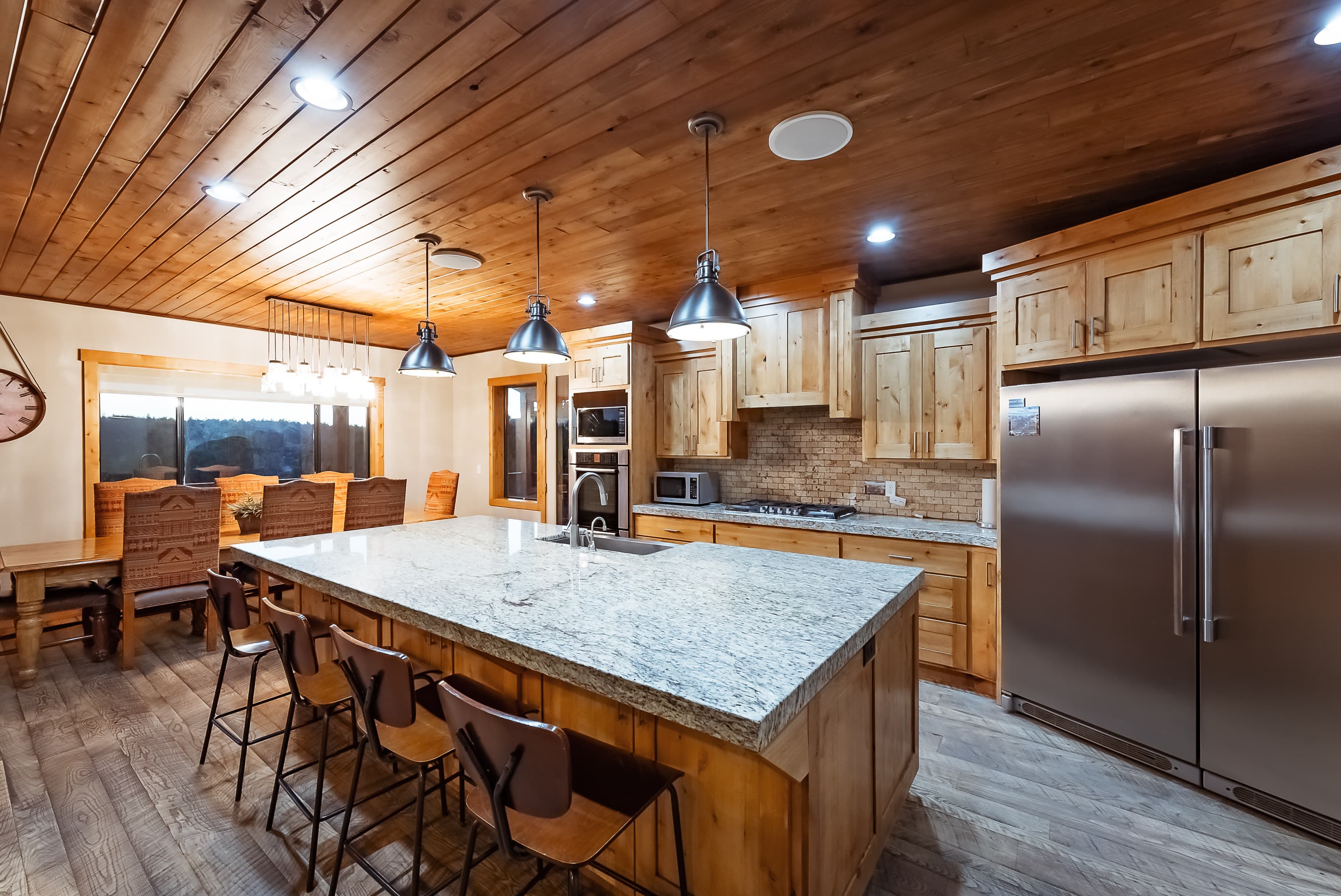A modern kitchen with wooden cabinets, granite countertops, and a spacious dining area.