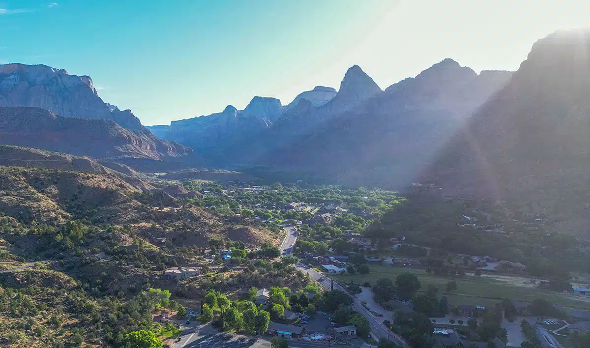 Aerial view of a lush valley surrounded by majestic mountains under a clear blue sky.