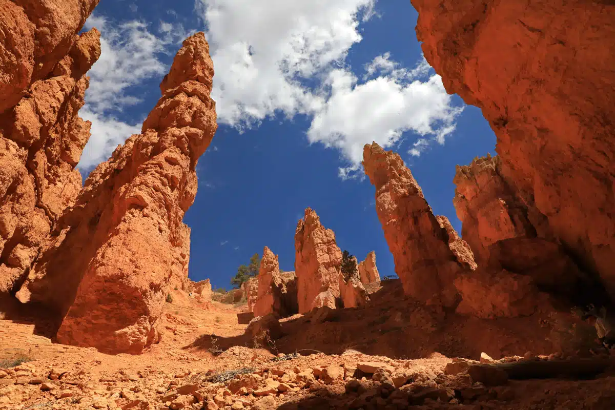 A view of tall, orange rock formations against a blue sky with wispy clouds.